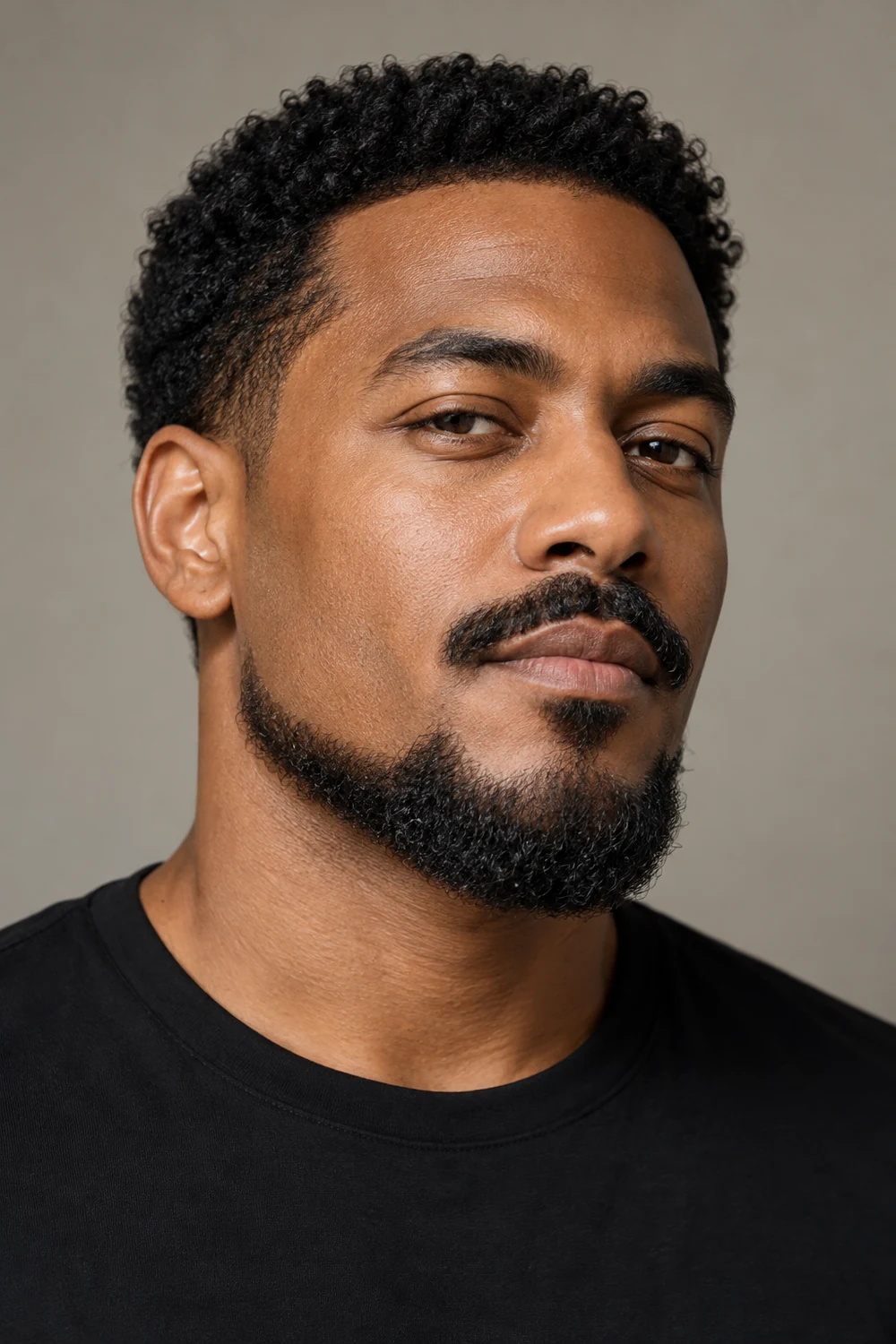Three-quarter portrait of an adult man with a curly Balbo beard, clean upper cheeks, disconnected sideburns, and a separate mustache.