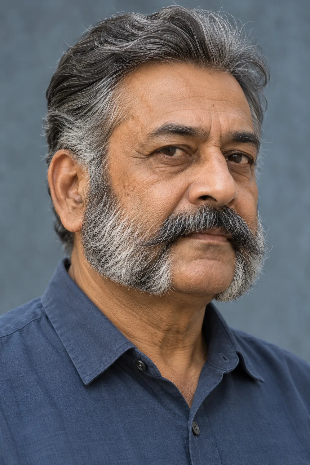 Older South Asian man with full gray mutton chops, a clean-shaven chin and a separate mustache.