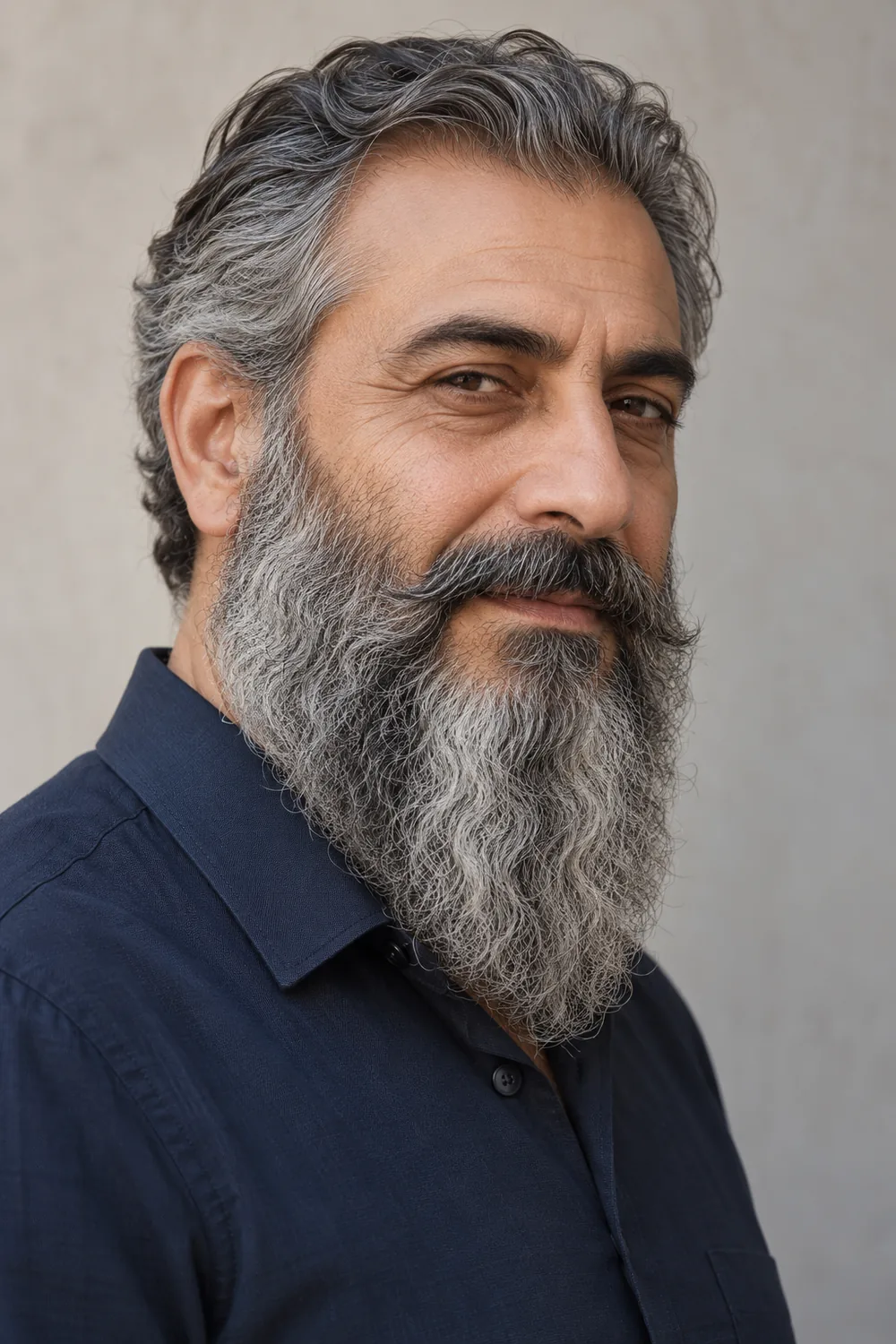 Three-quarter portrait of an adult man with a long wavy gray-and-dark tapered beard and a full mustache blended into the beard corners.