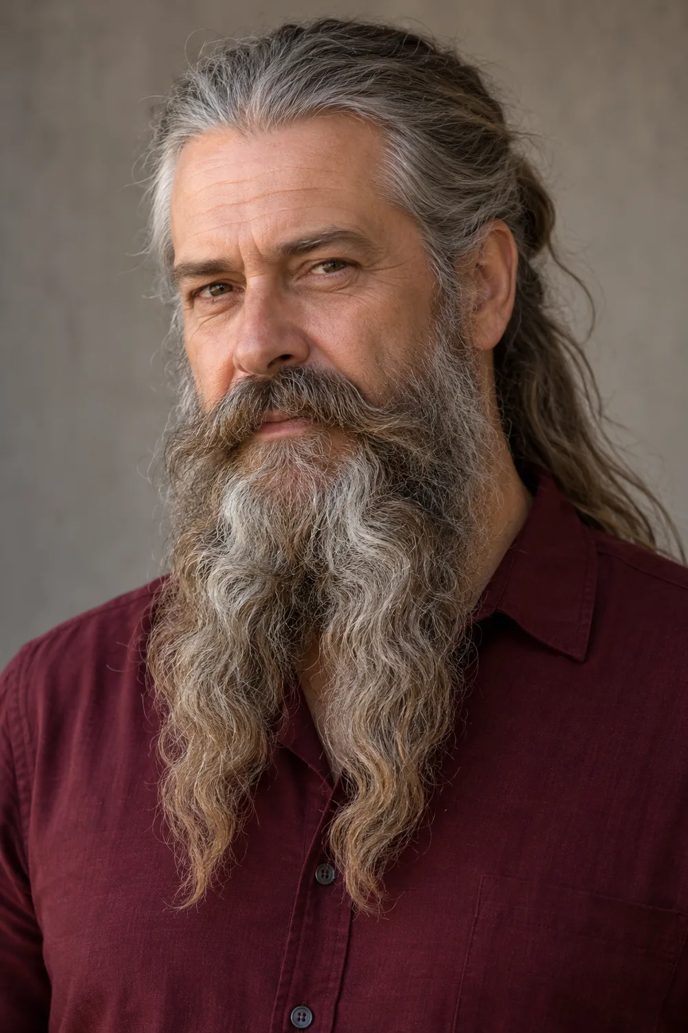Fictional adult man with long gray-brown hair tied back and a full wavy beard ending in two tapered points, paired with a connected natural mustache.