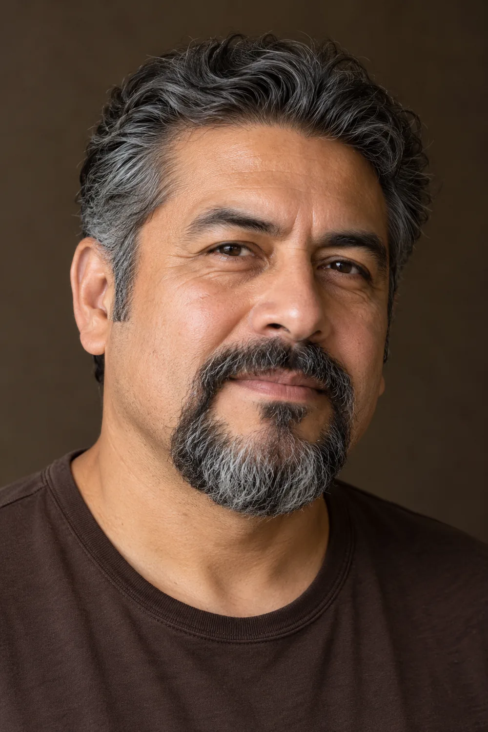 Three-quarter portrait of an adult man with wavy salt-and-pepper hair and a full circle beard, rounded chin, connected mustache, and shaved cheeks.