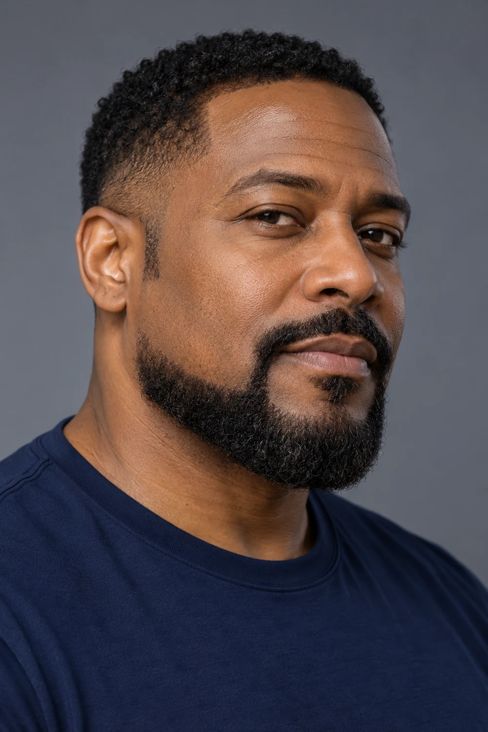 Three-quarter portrait of a Black man with a broad extended goatee, rounded chin, connected mustache, shaved upper cheeks, and tapered sideburns.