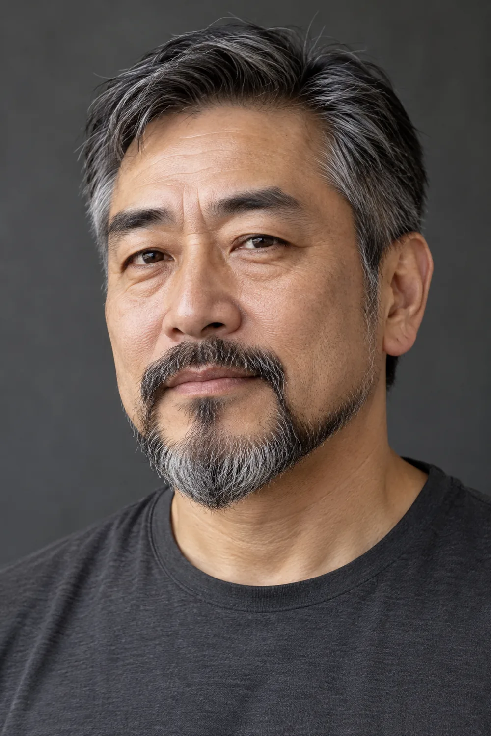 Three-quarter portrait of an East Asian man with a rounded salt-and-pepper extended goatee, softly curved cheek edge, connected mustache, shaved upper cheeks, and short disconnected sideburns.