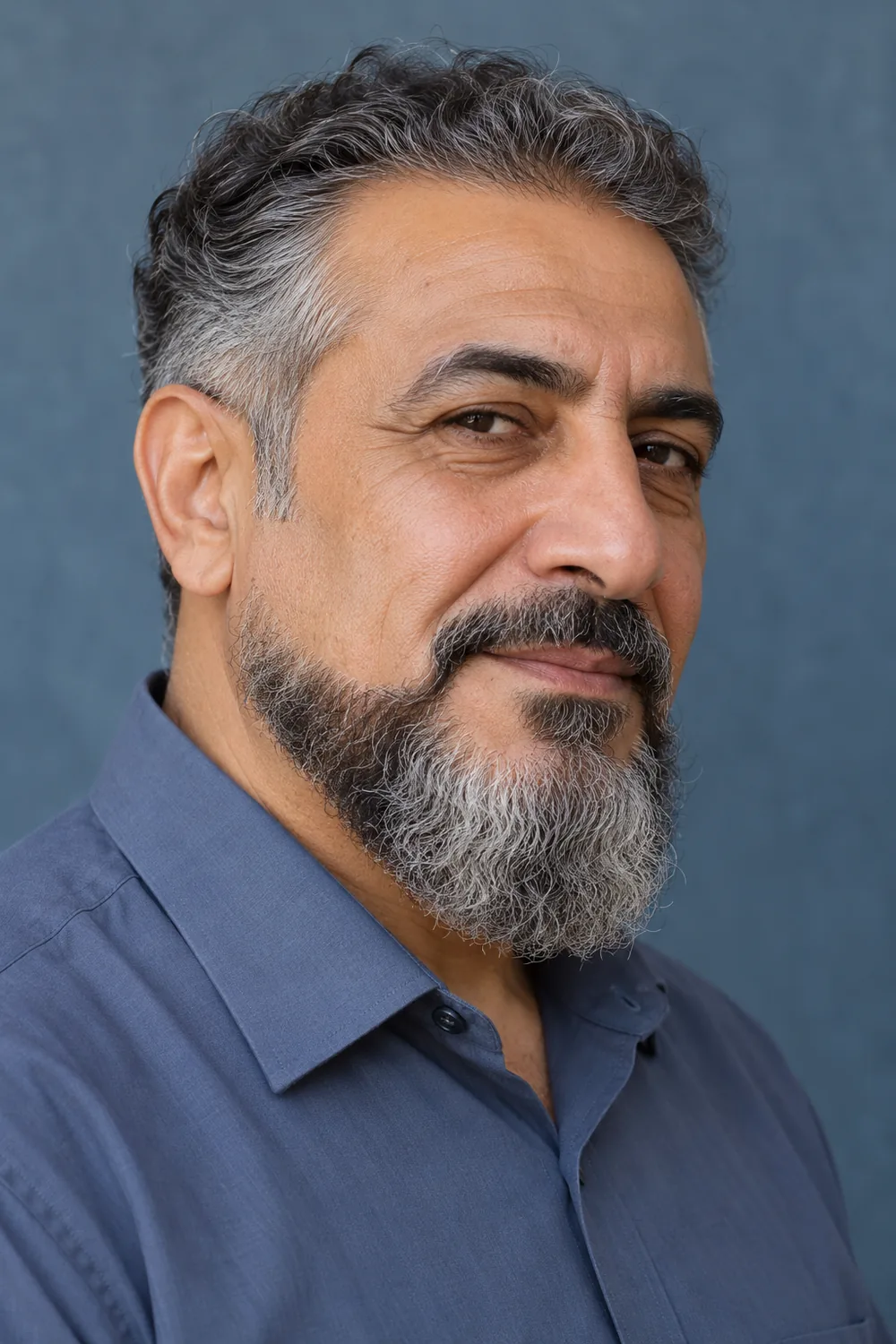 Three-quarter portrait of a mature man with a long, rounded extended goatee, low cheek edge, shaved upper cheeks and lightly connected mustache.