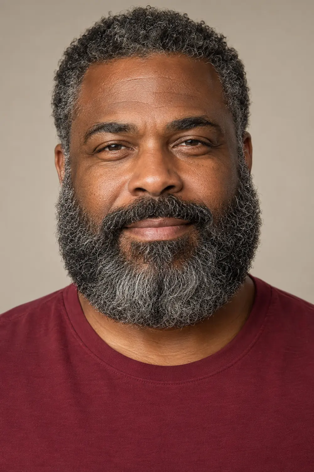 Frontal portrait of an adult Black man with a dense salt-and-pepper Garibaldi beard, broad rounded base, full sides, and connected mustache.