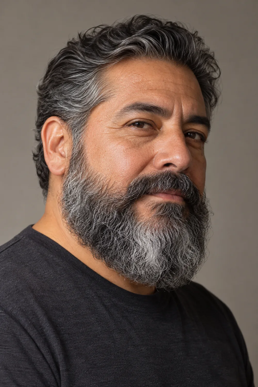 Three-quarter portrait of an adult man with dense salt-and-pepper hair, a broad wavy Garibaldi beard with full cheeks and a rounded base, and a connected mustache.