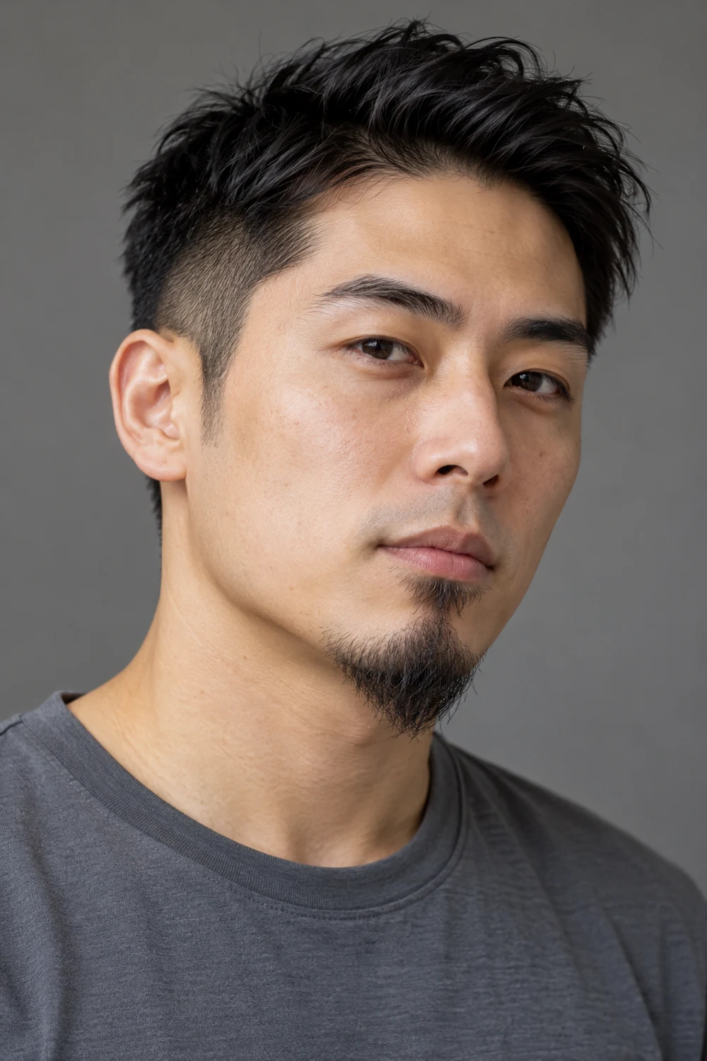 Three-quarter portrait of an East Asian man with a narrow pointed chin goatee, sparse natural texture, separate soul patch, and clean-shaven upper lip.
