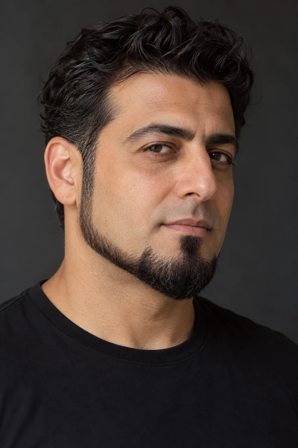 Three-quarter portrait of an adult man with a slim jawline beard joining a rounded chin goatee, a small chin-connected soul patch, clean cheeks, and a shaved upper lip.