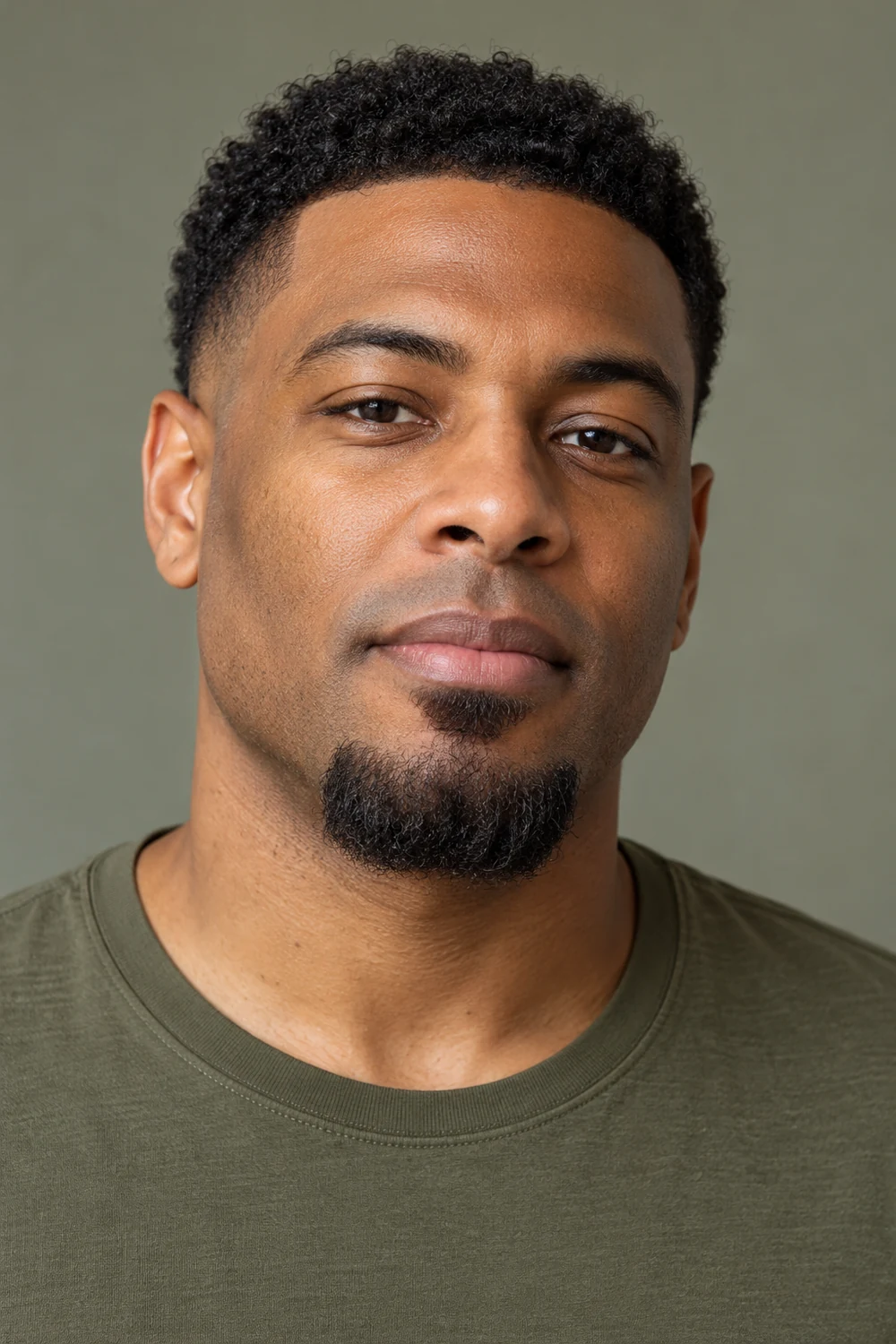 Near-frontal portrait of a man with a short chin goatee, a broad isolated soul patch, clean-shaven cheeks and upper lip.