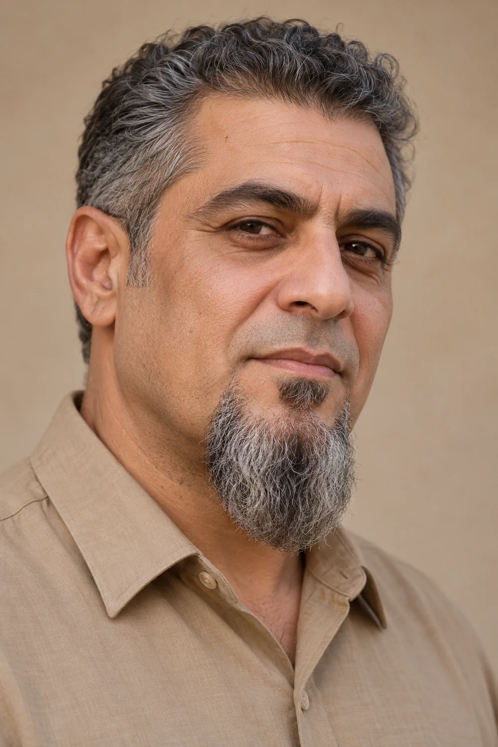 Three-quarter portrait of an adult man with a long, broad rounded gray-brown goatee, separate soul patch, and clean-shaven upper lip.