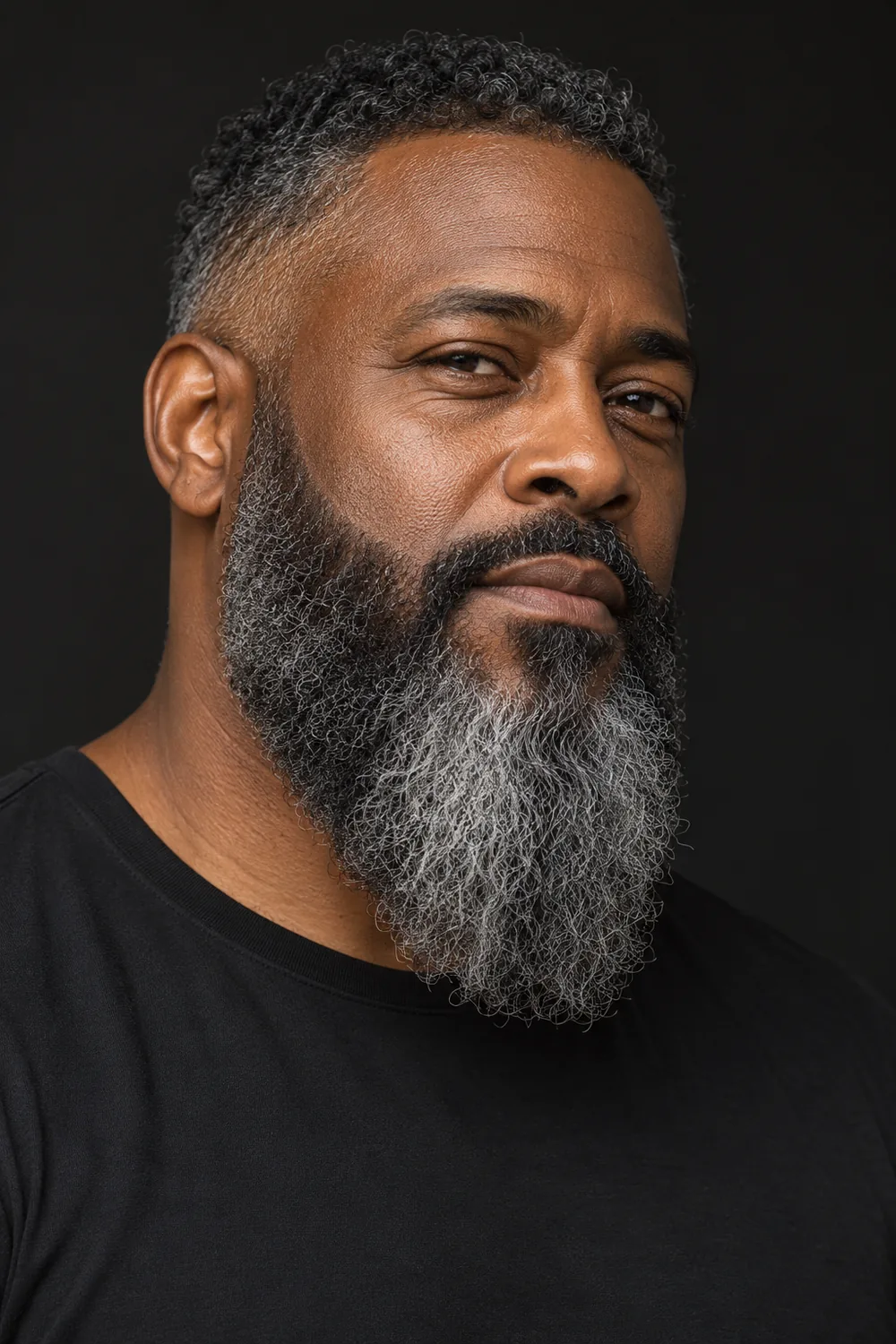 Three-quarter portrait of a man with a full salt-and-pepper beard, tapered cheeks, squared chin base, and gently faded sideburns.