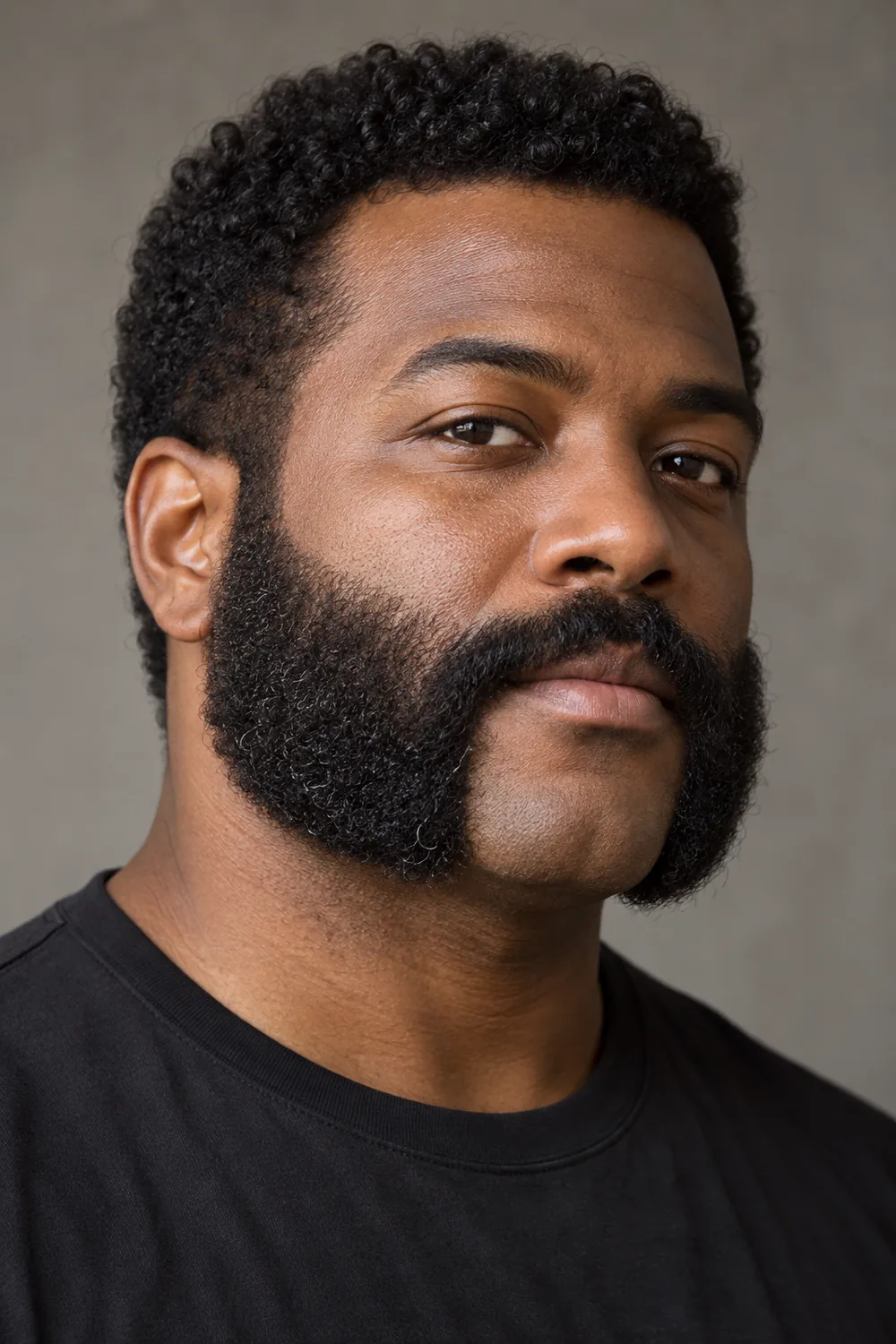 A Black man with broad, dense mutton chops, a high cheek line, connected mustache, and clean-shaven chin.