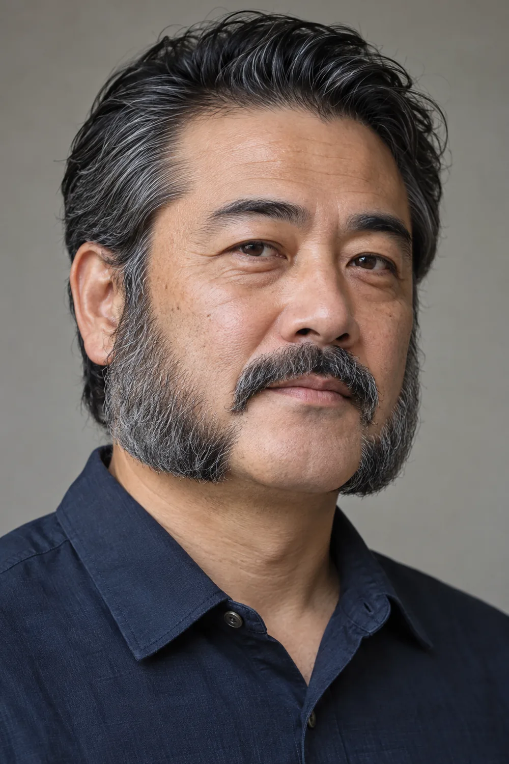 A Japanese man with broad salt-and-pepper mutton chops ending at the jaw, a clean chin, and a medium mustache separated by visible shaved gaps.