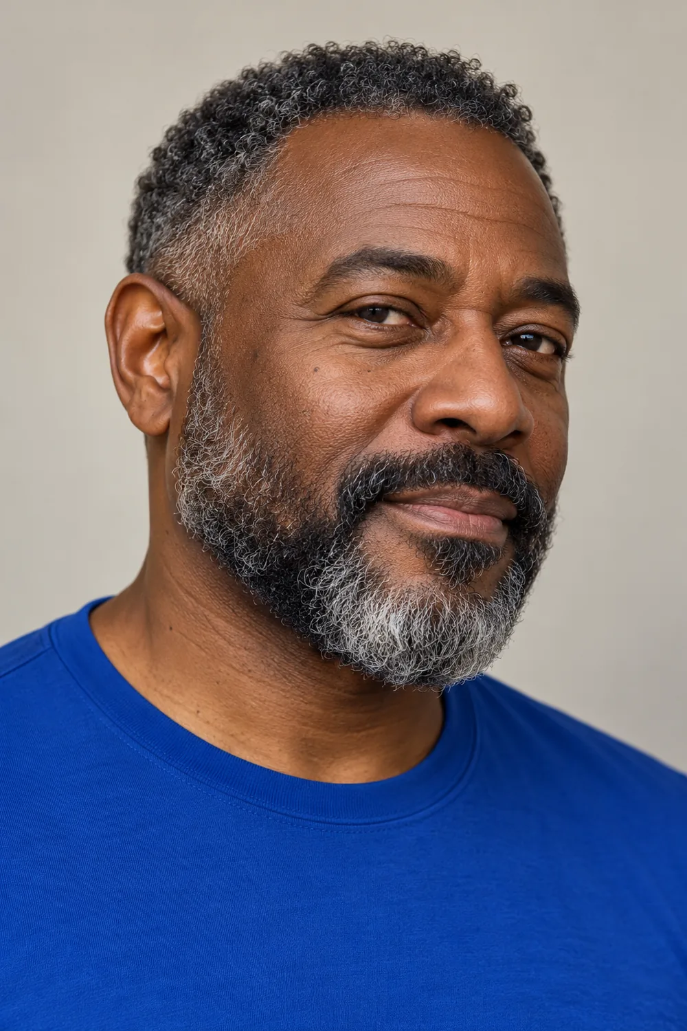 Three-quarter portrait of an adult Black man with a short coily salt and pepper beard, rounded chin, and broad chevron mustache.