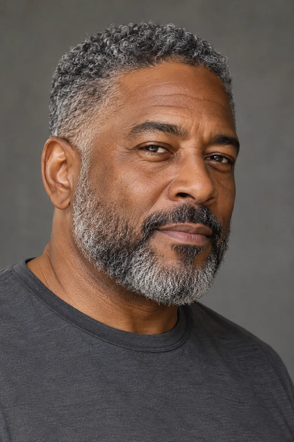 Three-quarter portrait of a mature Black man wearing a short, connected salt-and-pepper beard with a softly squared jaw outline.