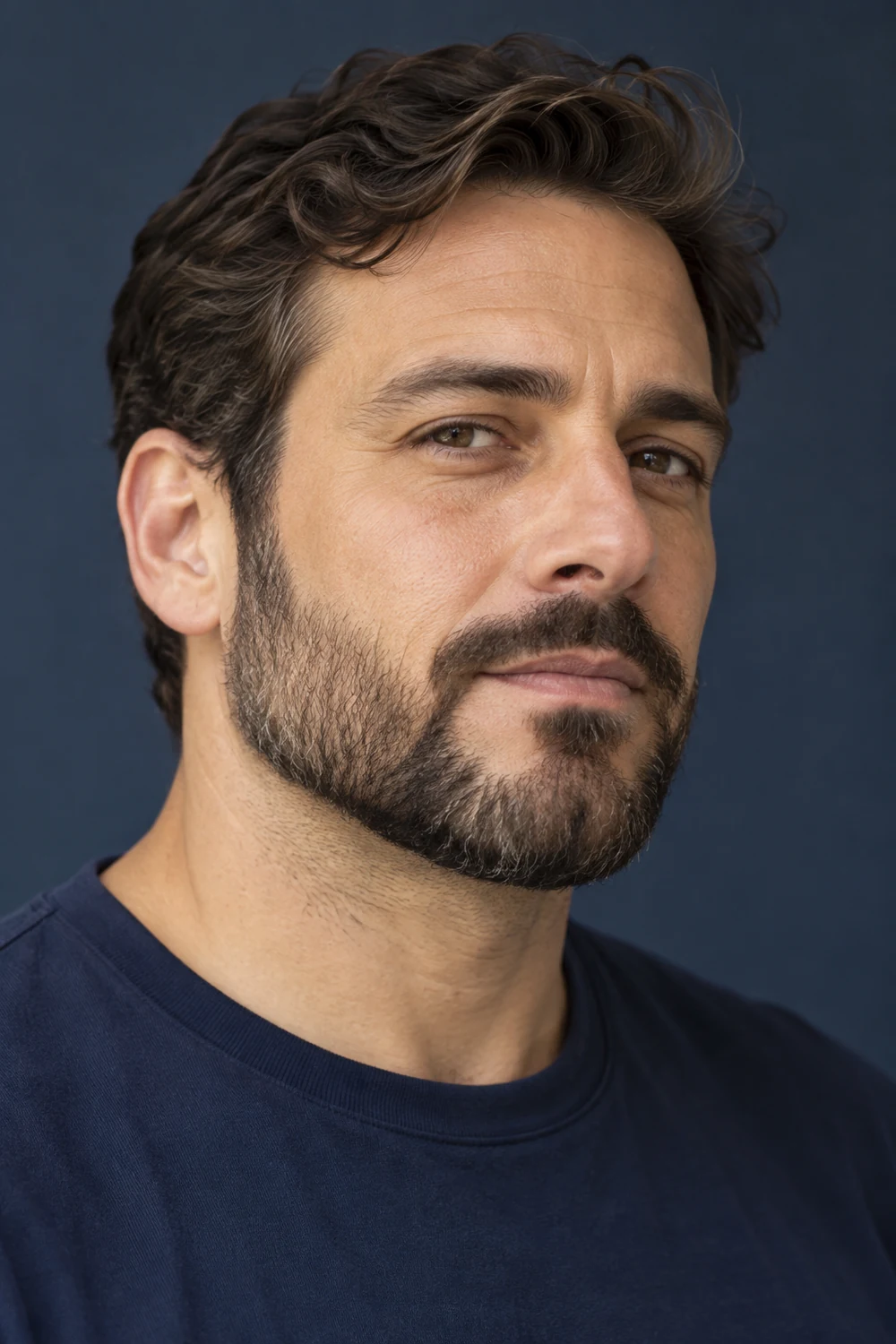 Three-quarter portrait of an adult man with a short boxed beard, softly rounded jaw corners, a natural mid-height cheek line, connected narrow mustache and clean neckline.