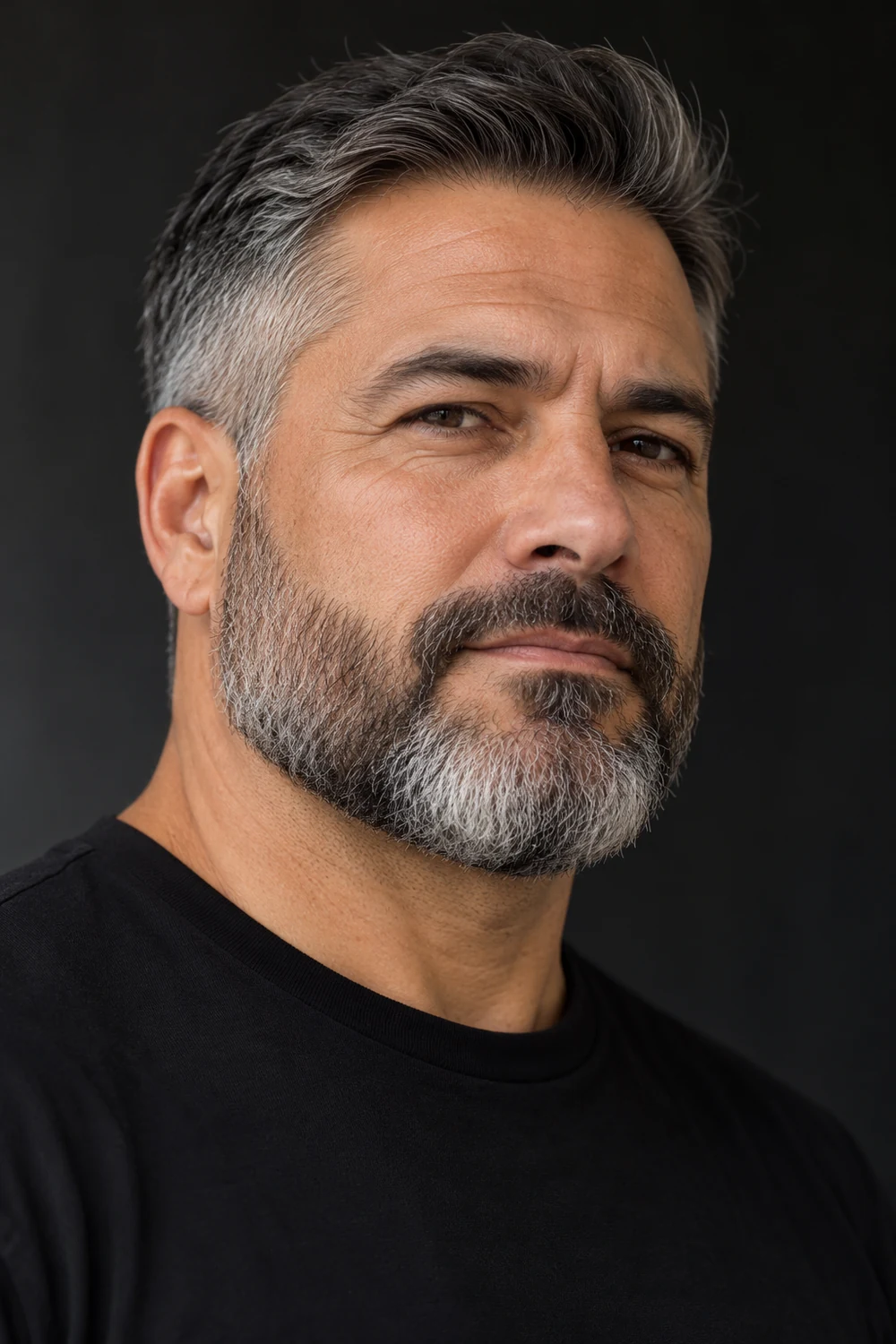 Fictional adult man in a black crewneck, shown in three-quarter view with a short salt-and-pepper boxed beard, broad squared chin, softly defined cheek line, blended sideburns and connected mustache.